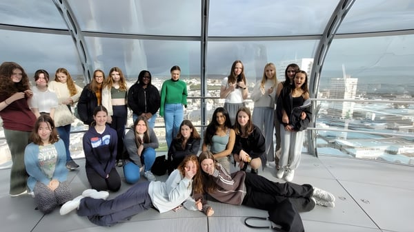 Un grupo de alumnas de Brighton Girls posan juntas en una sala acristalada con vista a la ciudad.