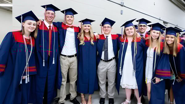 Un grupo de absolventes de la Brisbane State High School celebra en sus togas rojas y azules en el pasillo su graduación.