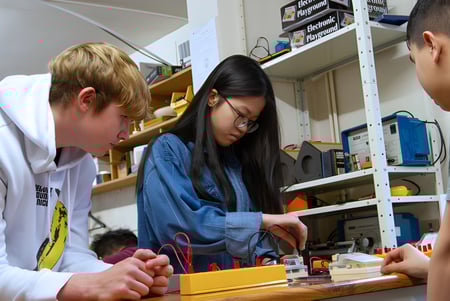 Tres estudiantes trabajan juntos en un proyecto en un aula en el campus del Brooke House College.