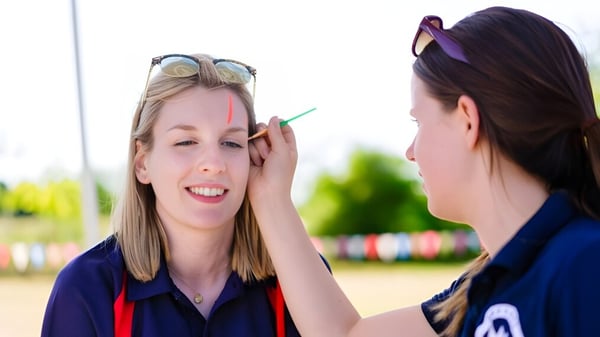 Dos alumnas de Brookes UK realizan una interacción lúdica al aire libre con gafas de sol coloridas y decoraciones.