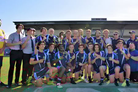 Un grupo de estudiantes de la Bundaberg State High School posan frente a un edificio con un mural colorido.