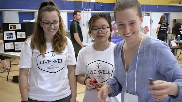Tres alumnas y alumnos con camisetas de Live Well están juntos en un aula de Burlington Central High School.