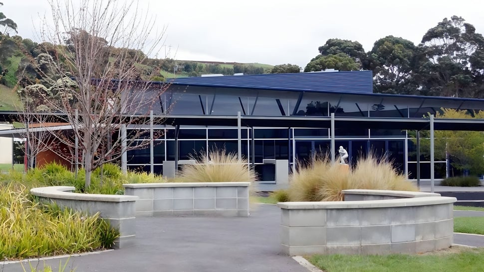 El moderno edificio de vidrio y acero con techo inclinado en el campus de la Burnie High School está rodeado de jardines bien cuidados.