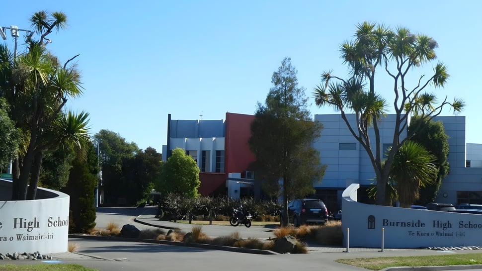 El campus de la Burnside State High School con palmeras y un moderno edificio de varios pisos al fondo.