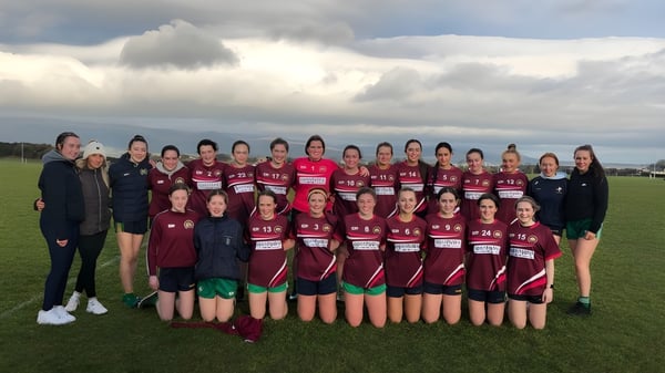 Un grupo de jóvenes alumnas de la Bush Post Primary School posan en un campo cubierto de hierba con un paisaje montañoso de fondo.