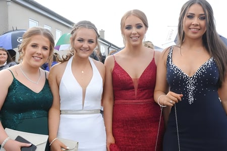 Cuatro alumnas de la Bush Post Primary School posan juntas en ropa formal al aire libre.