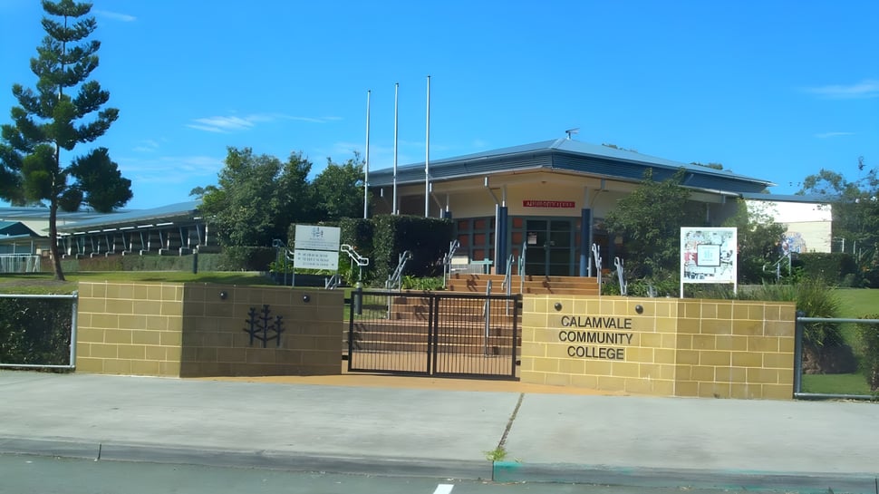 El edificio de ladrillo con el letrero Calamvale Community College se encuentra frente a árboles y una zona verde.