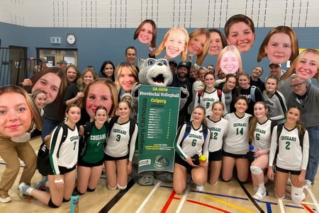 Un grupo de jóvenes jugadoras de baloncesto posan en el gimnasio frente a un gran banner que dice Calgary Christian School.