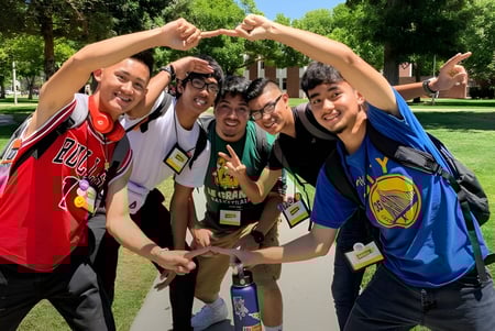 Un grupo de estudiantes posa en el parque frente a los árboles en el campus de la California State University Long Beach.