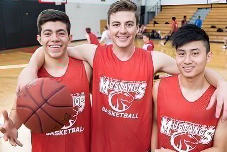Tres estudiantes del Caloundra Christian College en camisetas rojas de baloncesto posan con un balón de baloncesto en el gimnasio.