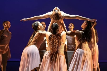 Un grupo de bailarinas en vestidos claros se presenta en el escenario de la Calvary Christian Academy.