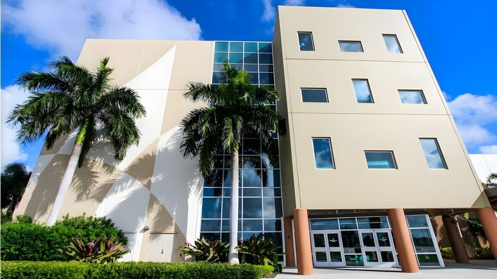 El edificio de varios pisos de la Calvary Christian Academy está rodeado de palmeras tropicales y se encuentra bajo un cielo azul claro.
