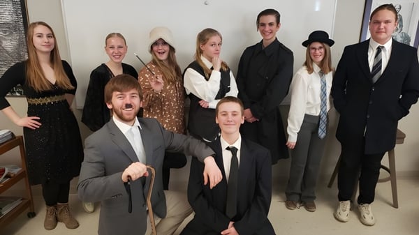 Un grupo de estudiantes de la Cambridge Christian School está junto a una pared blanca en un marco formal.