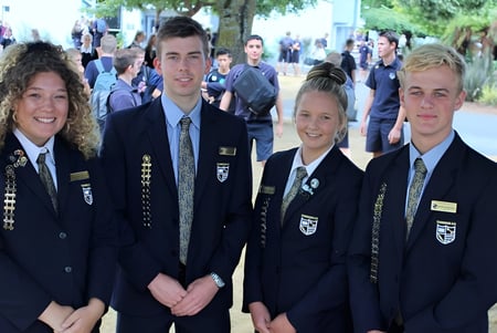 Un grupo de estudiantes de la Cambridge High School está junto en el campus escolar al aire libre.