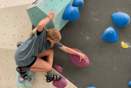 Una estudiante está escalando en la colorida pared de escalada en el área de escalada del Canberra College.