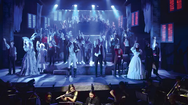 Un gran grupo de alumnas y alumnos de la Canford School está vestido con ropa formal en el escenario durante una actuación.