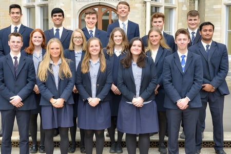 Un grupo de alumnas y alumnos de la Canford School está vestido con ropa formal frente a un edificio histórico.
