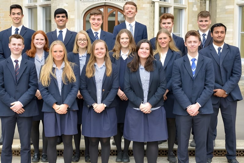 Un grupo de alumnas y alumnos de la Canford School está vestido con ropa formal frente a un edificio histórico.