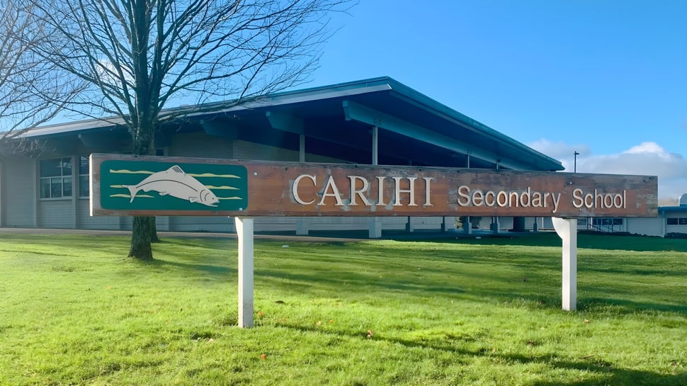 El edificio de la Carihi Secondary School está frente a un campo de hierba y un cielo azul.