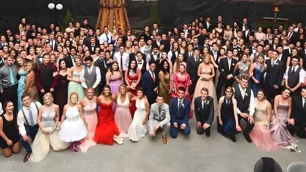 Estudiantes de la Carihi Secondary School se reúnen en un evento formal en una sala elegante con candelabro.