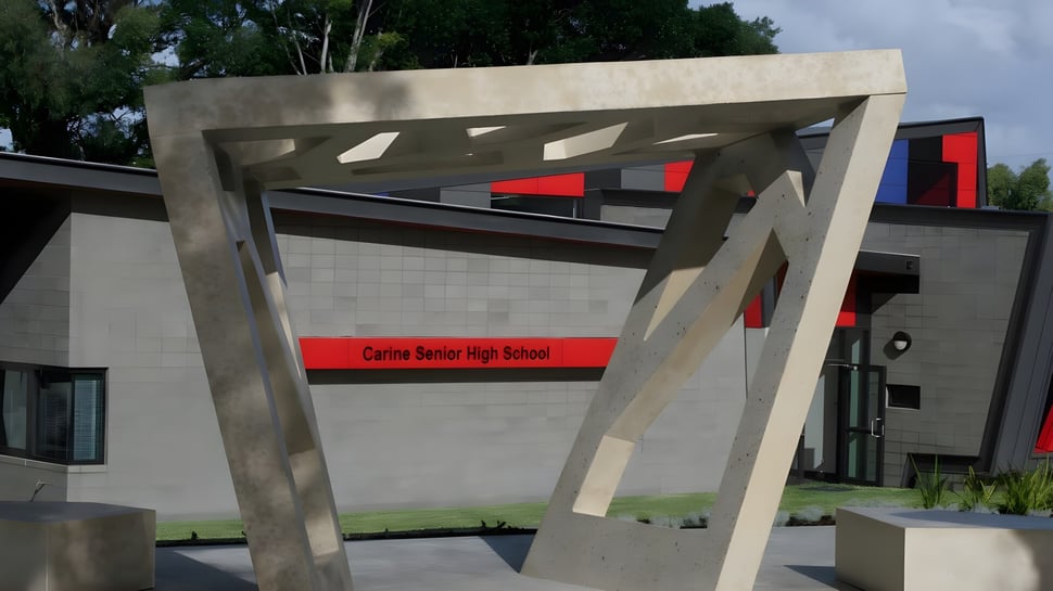 El edificio de la Carine Senior High School está rodeado de árboles y áreas verdes.