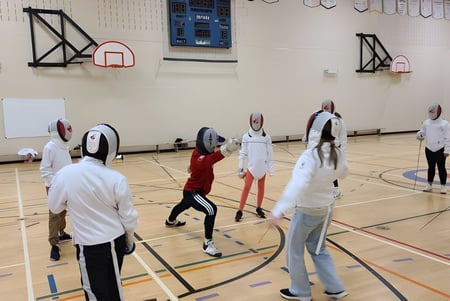 Un grupo de estudiantes en el gimnasio con canastas de baloncesto en el campus de la Carrefour de l’Acadie.