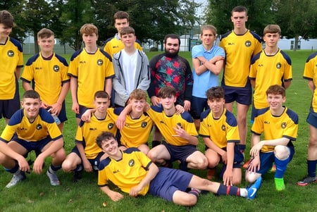 Un grupo de jóvenes futbolistas posando en un campo en el campus del Carrignafoy Community College.