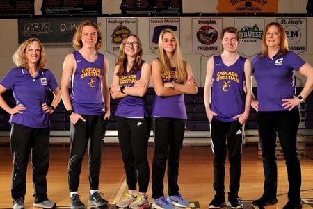 Un grupo de seis estudiantes en uniformes morados está en el gimnasio de la Cascade Christian High School.