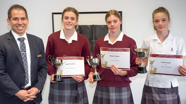 Cuatro estudiantes de la Cashmere High School presentan orgullosamente sus premios y trofeos.
