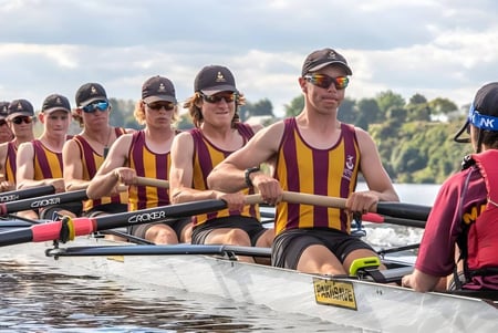 Estudiantes de la Cashmere High School remando en un cuerpo de agua con un paisaje de fondo.