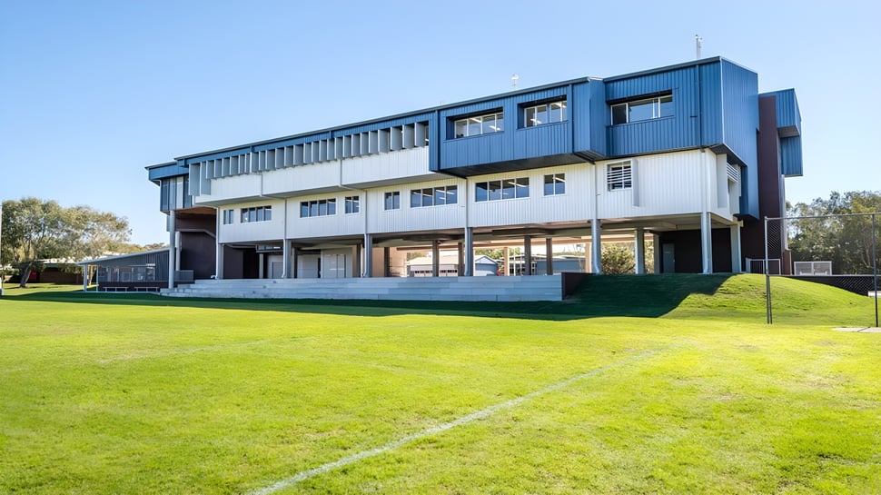 El moderno edificio de varios pisos de la Castlerea Community School se encuentra en un prado rodeado de árboles bajo un cielo azul.