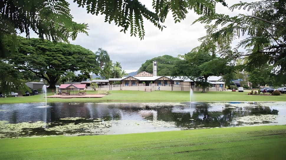 Un parque verde con un estanque y una cabaña de madera en el terreno de la Cathedral School of St Anne & St James.
