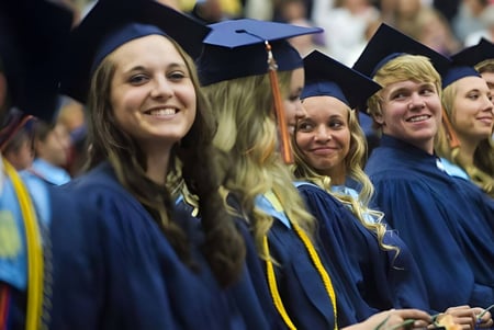Las graduadas y graduados de la Catholic Central High School están juntos en un grupo con sus togas azules y amarillas.