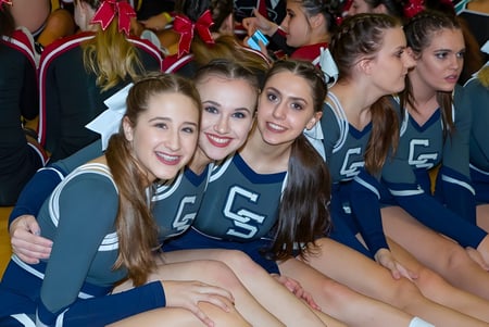 Un grupo de jóvenes animadoras posan en el Cave Creek Unified School District en sus uniformes en el gimnasio.