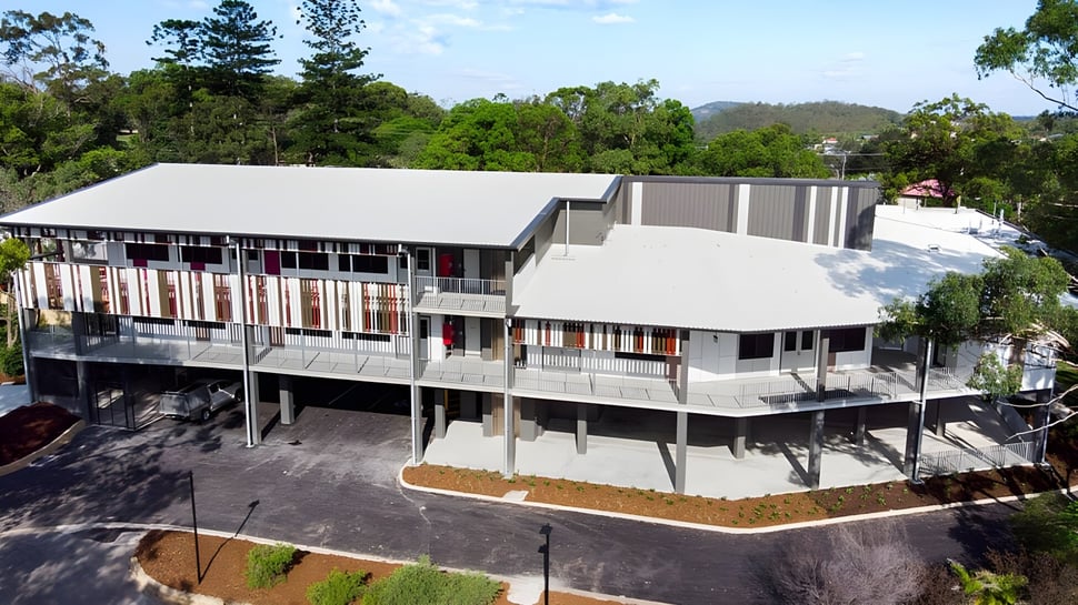 El moderno edificio de varios pisos de la Cavendish Road State High School está rodeado de un paisaje boscoso.