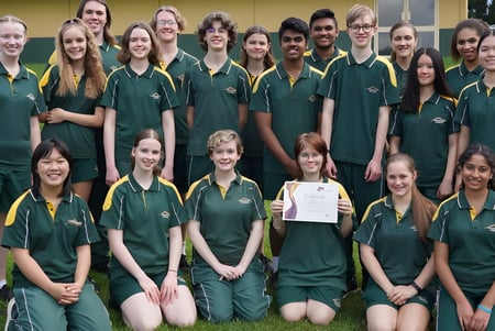 Un grupo de alumnas y alumnos de la Centenary Heights State High School está de pie en un campo de césped en el terreno escolar.