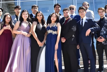 Estudiantes de la Centennial Secondary School en ropa formal posando frente a un edificio de vidrio.