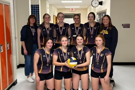 Un grupo de jugadoras de voleibol está en el pasillo de la Central High Sedgewick Public School en sus uniformes escolares.