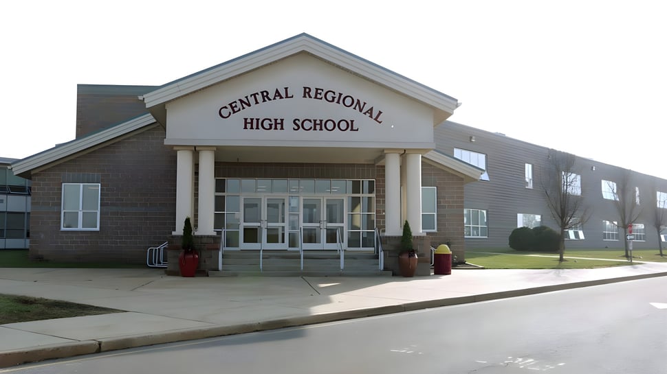 Se puede ver el edificio de ladrillo de dos pisos con la entrada de la Central Regional High School y el área pavimentada circundante.
