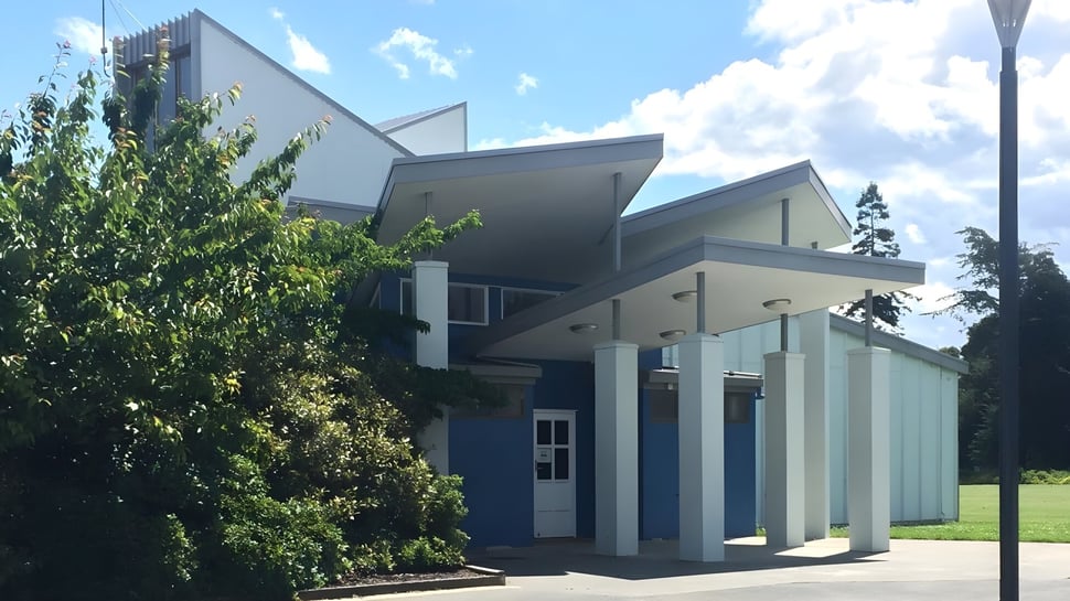 El moderno edificio del Central Southland College con grandes ventanas y una entrada ajardinada bajo un cielo azul.