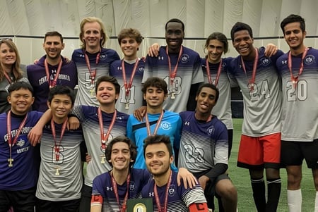 Un grupo de estudiantes de la Central Toronto Academy posan con ropa deportiva y medallas frente a una instalación deportiva.