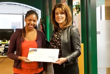 Dos estudiantes sostienen en el Centre High Campus un certificado frente a una pared verde con objetos de exhibición.