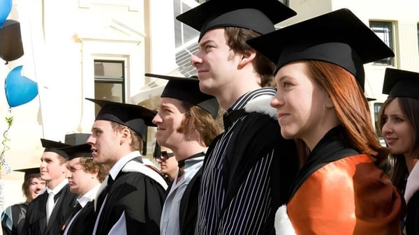 Un grupo de graduados y graduadas en togas celebra su graduación en la Centre Wellington District High School.