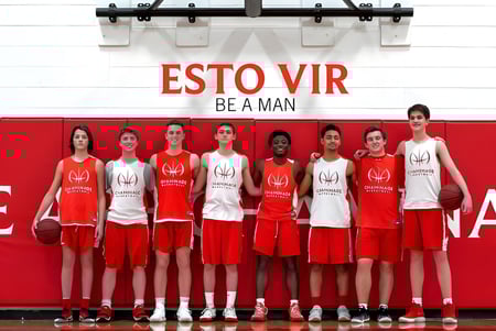 El equipo de baloncesto de la Chaminade College Preparatory School posa junto a un fondo rojo con la inscripción ESTO VIR BE A MAN.