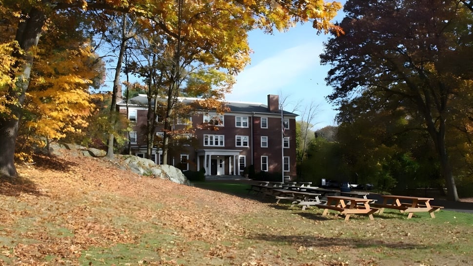 El histórico edificio de Chapel Hill - Chauncy Hall está rodeado de colorido follaje de otoño y una colina cubierta de hierba con bancos de madera.