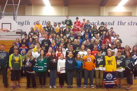 Un grupo de estudiantes en el gimnasio de la Charles Bloom Secondary School frente a un mensaje motivacional en la pared.