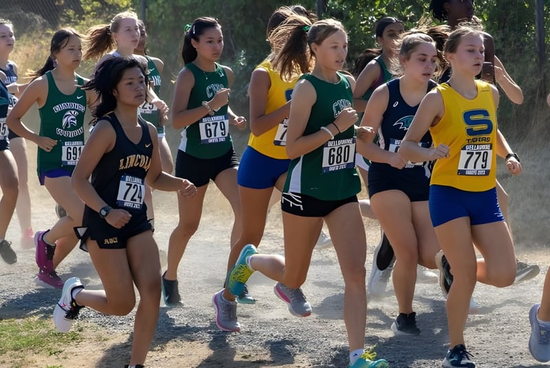 Estudiantes de la Charles Wright Academy corren en una carrera de campo a través con un fondo boscoso.