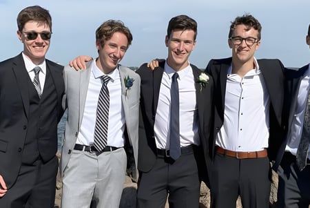 Cinco estudiantes de la Charlottetown Rural High School están juntos en ropa formal frente a un cuerpo de agua.