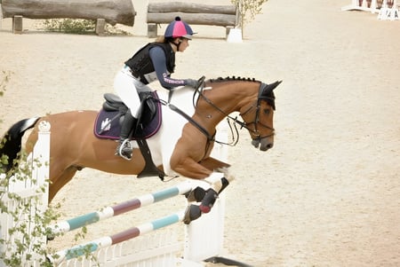 Una estudiante de la Charterhouse School salta con su caballo sobre un obstáculo en una instalación al aire libre.