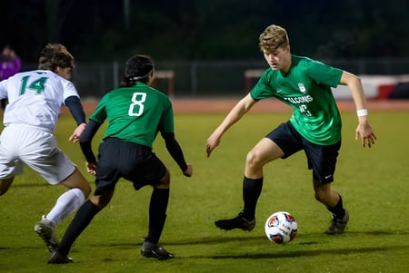 Estudiantes de la Chatelech Secondary School juegan un partido de fútbol en el campo deportivo por la noche.